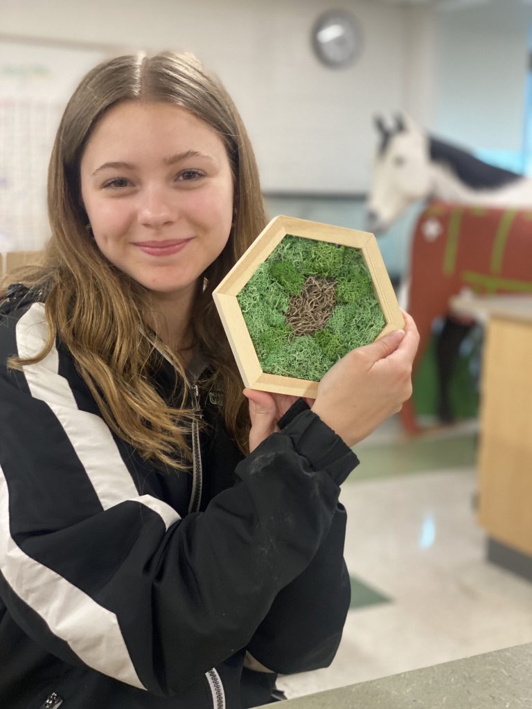 Landscape design student holding up moss art