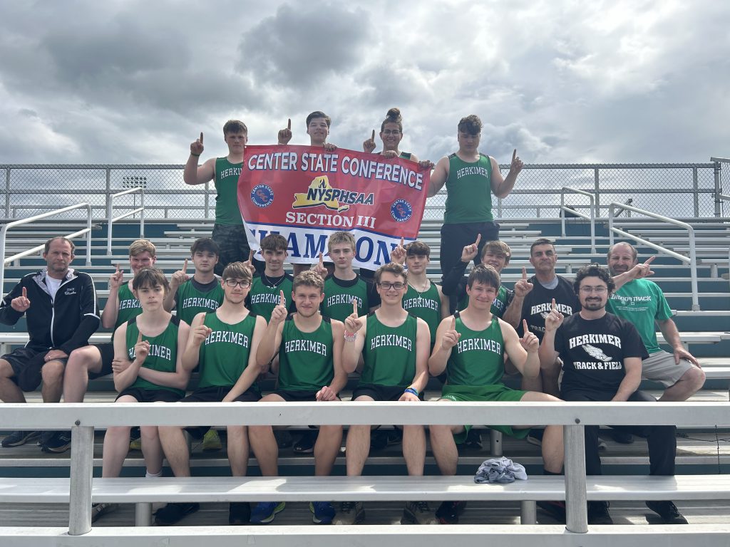 Boys track and field team posing on bleachers with CSC league championship banner