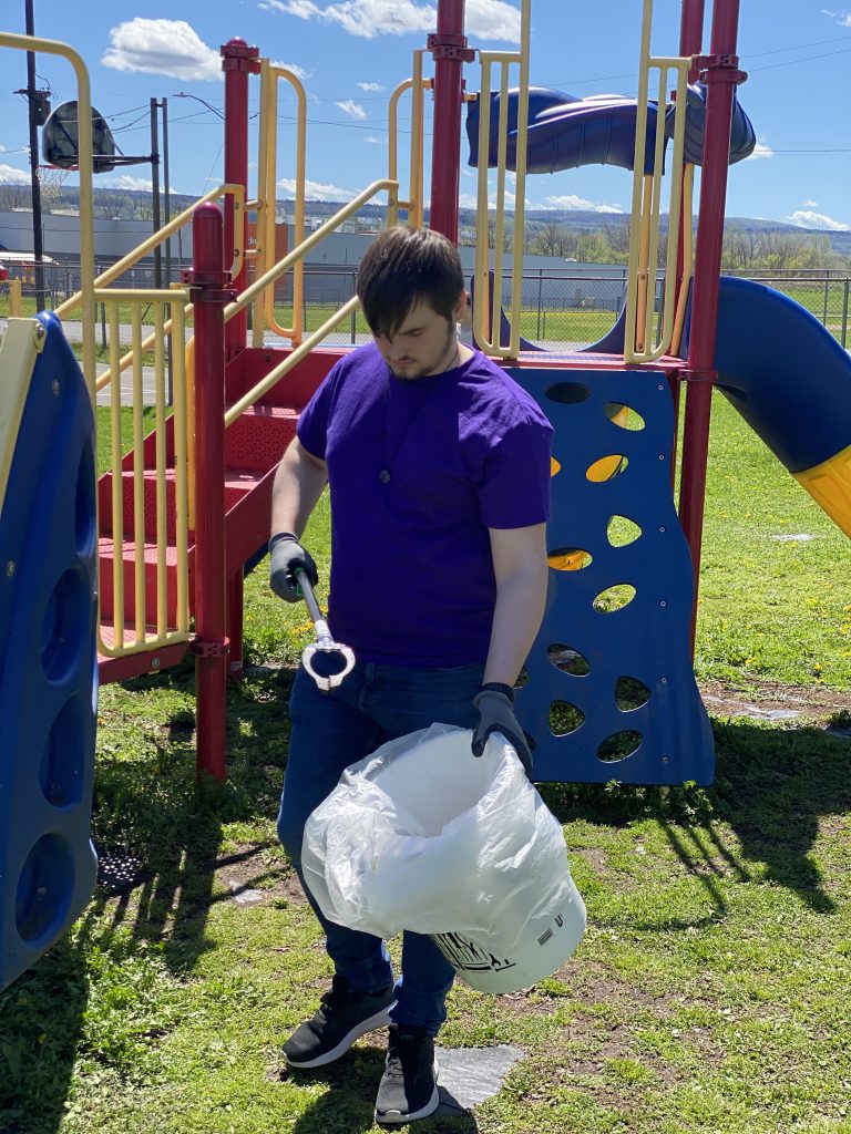 Student cleaning up at Harmon Park in front of playground