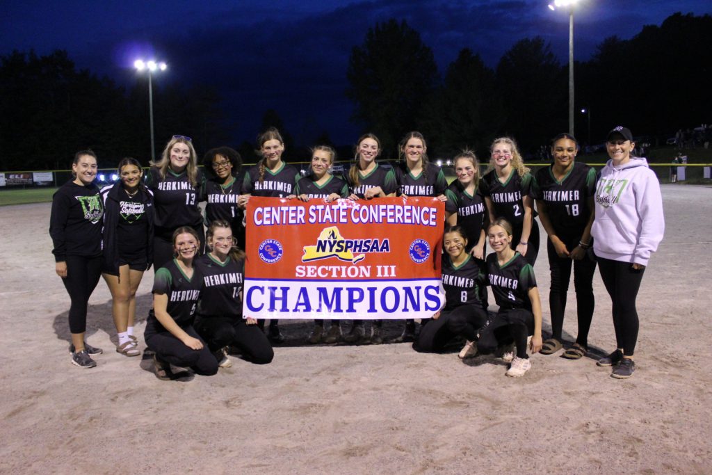Softball champs and coaches posing with banner