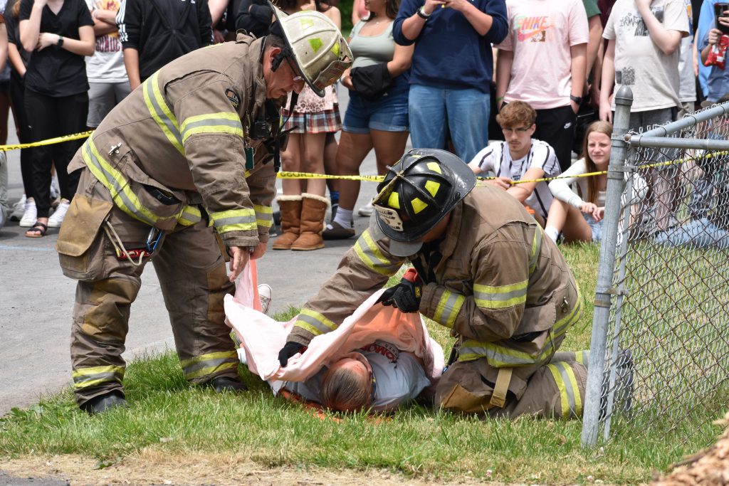 Two firefighters cover up student in mock crash