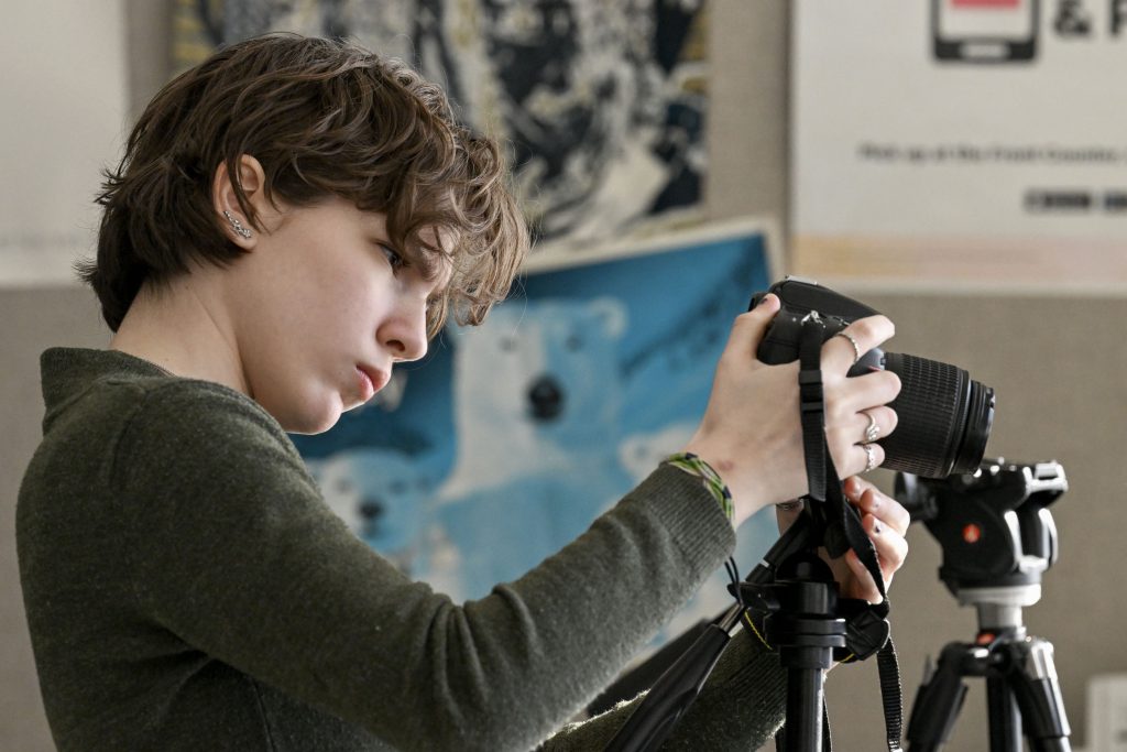 A Visual Arts student examines the display screen of a large camera.