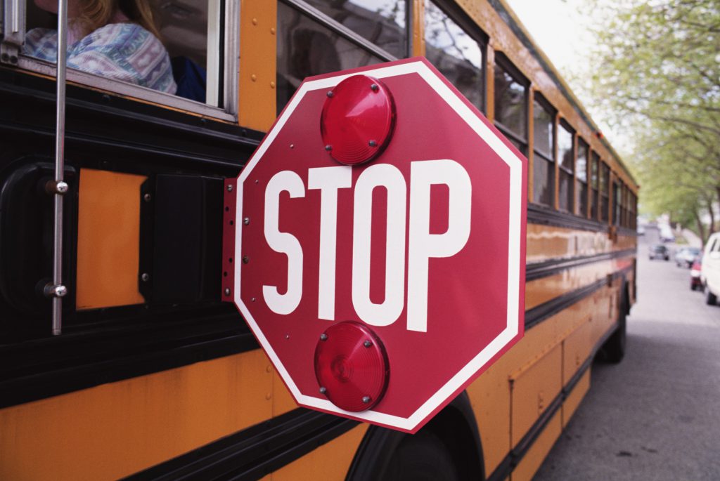 A school bus stop sign extended fully during a stop.