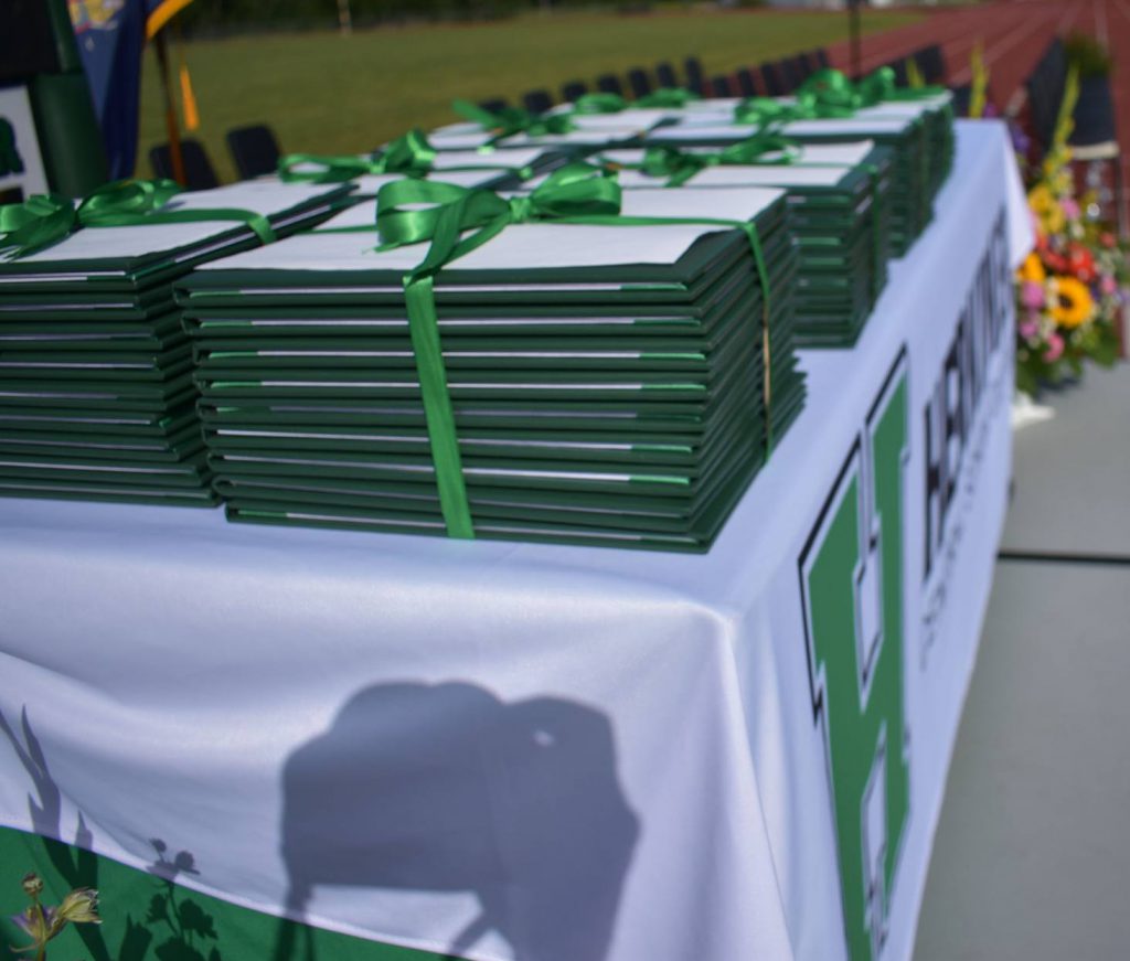 Stacks of diplomas sit on a table before the graduation ceremony.