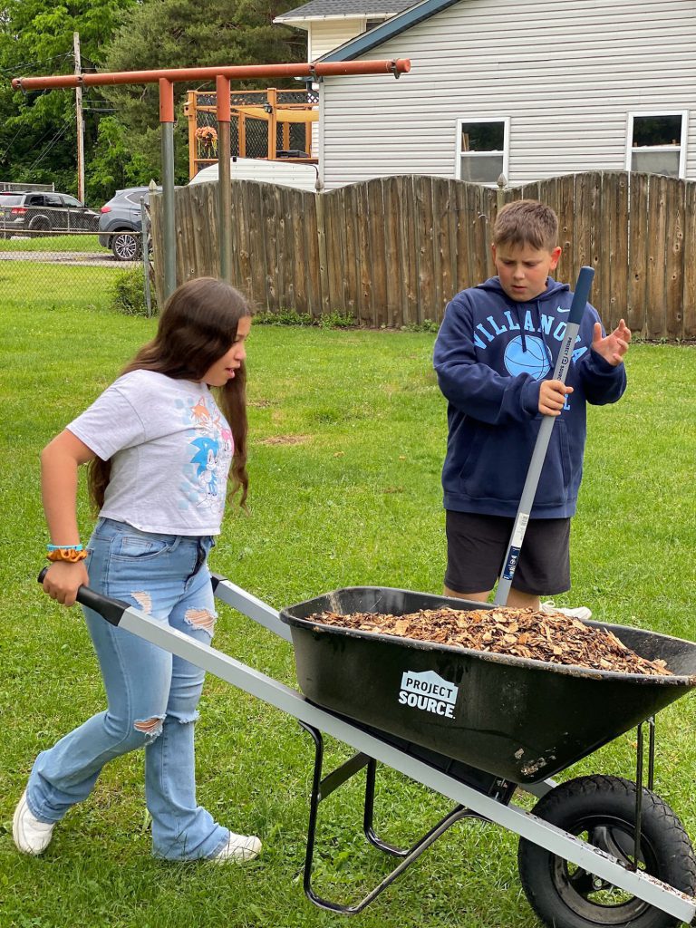 Students using a wheelbarrow to garden at Harmon Park