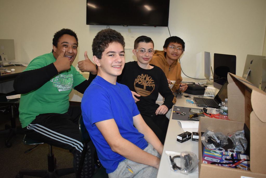 Four students posing for a photo while working on building a drone.