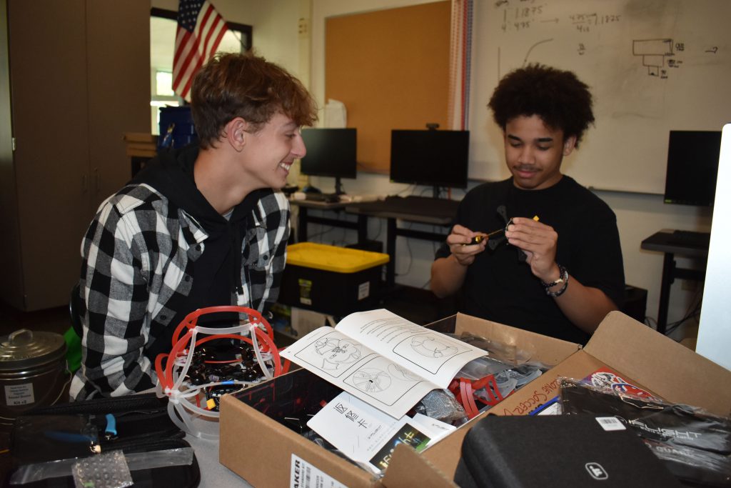 Two students working on building a drone.