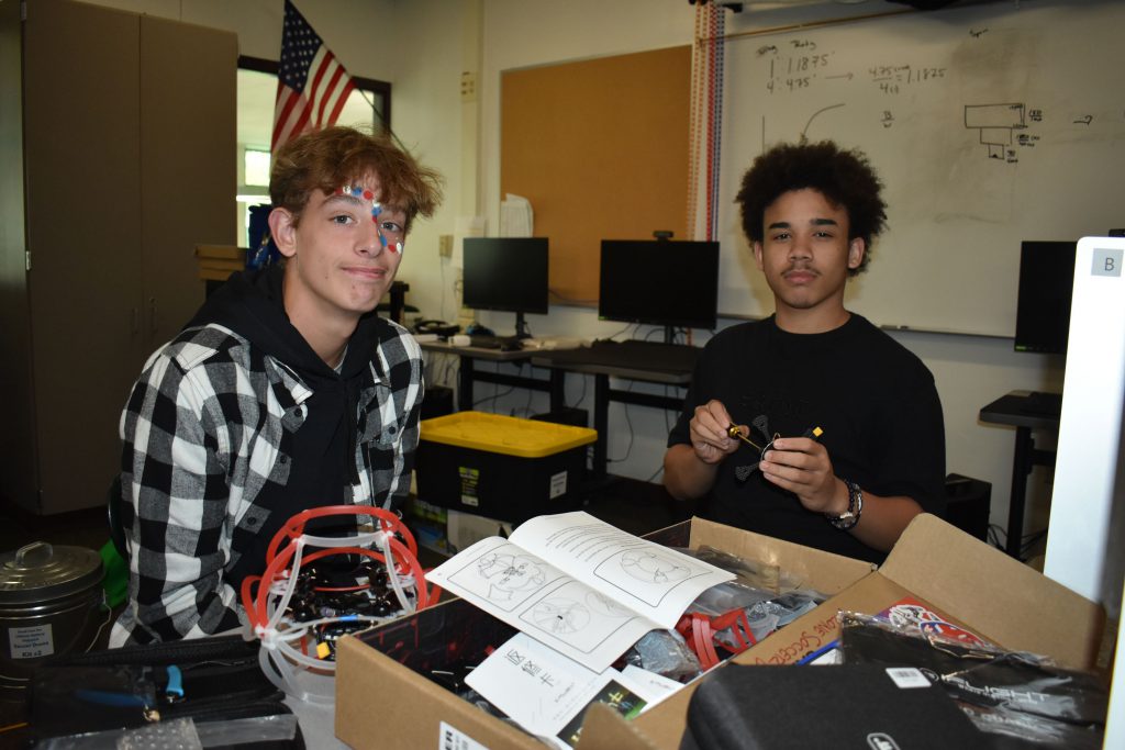 Two students posing for a photo while working on building a drone.