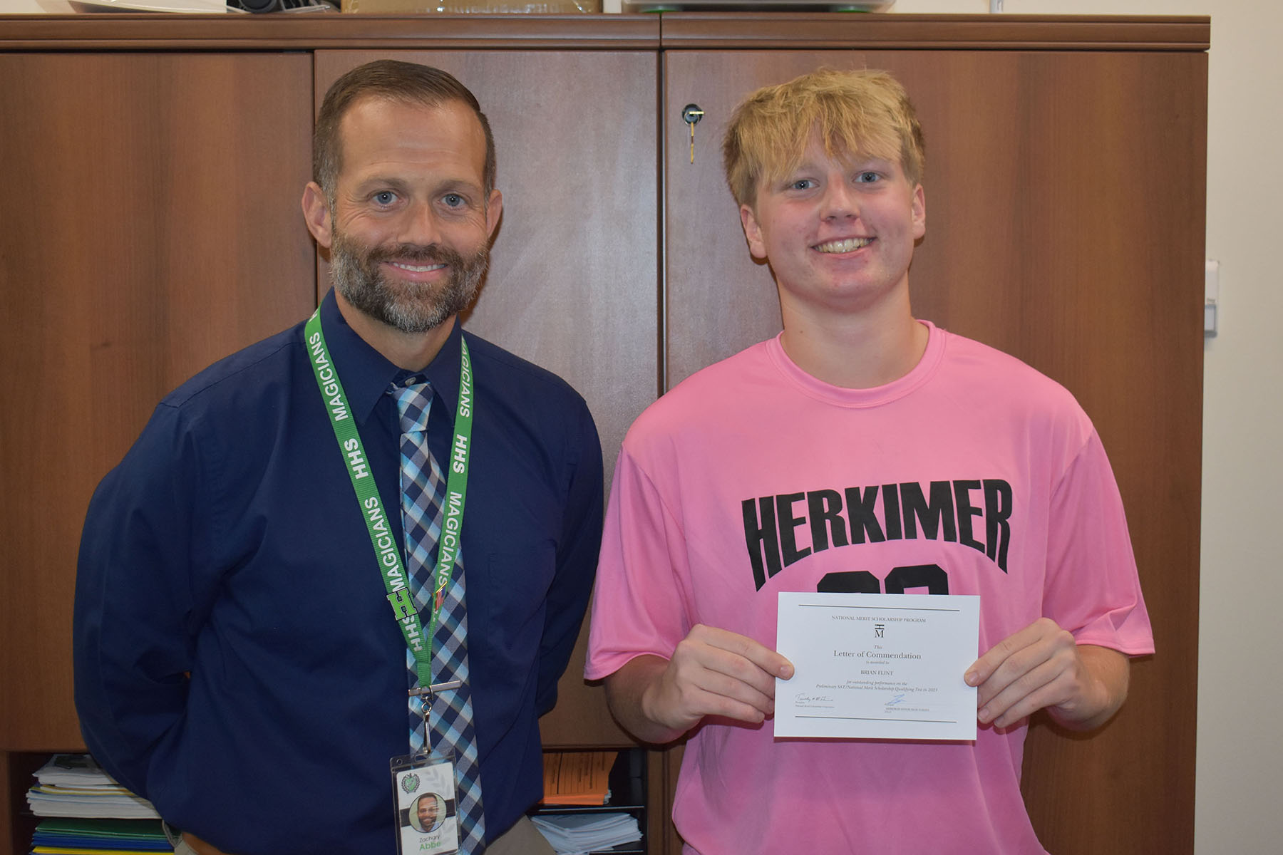 Principal and student with the student holding a letter of commendation