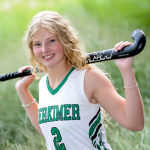 Student Audrey McDonnell in a field hockey uniform and holding a field hockey stick.