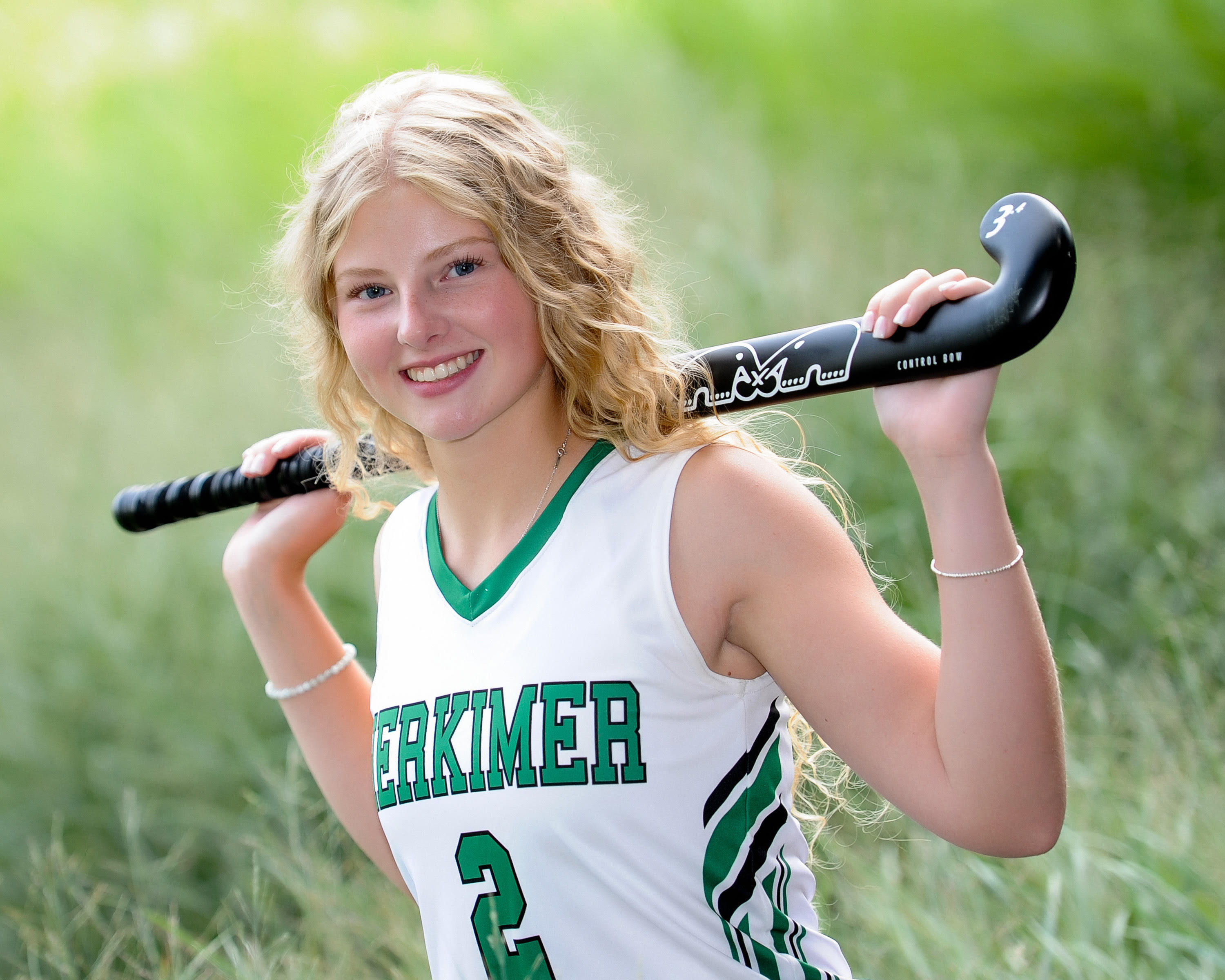 Student Audrey McDonnell in a field hockey uniform and holding a field hockey stick.