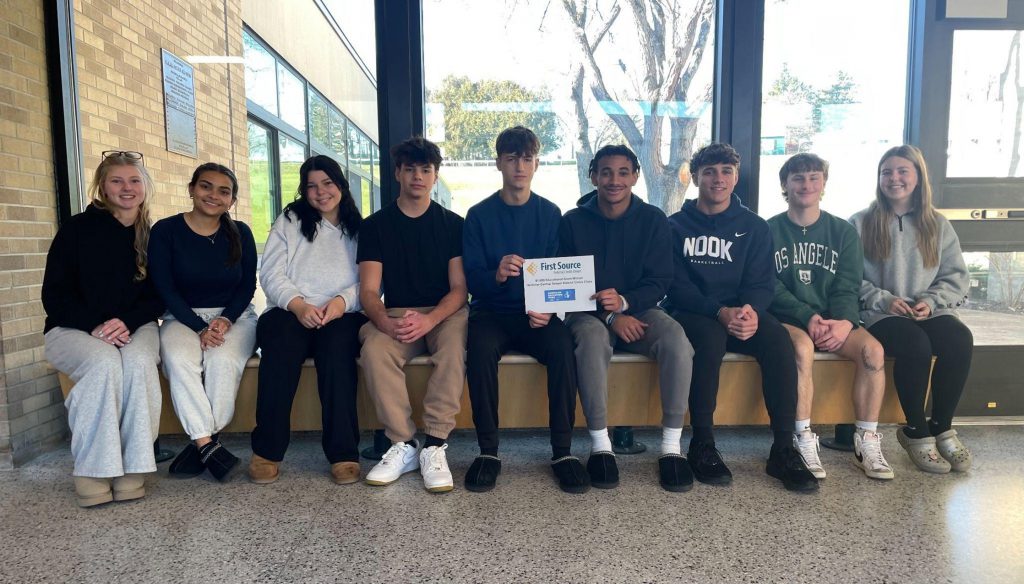 Nine civics students sitting and posing with their grant from First Source Federal Credit Union