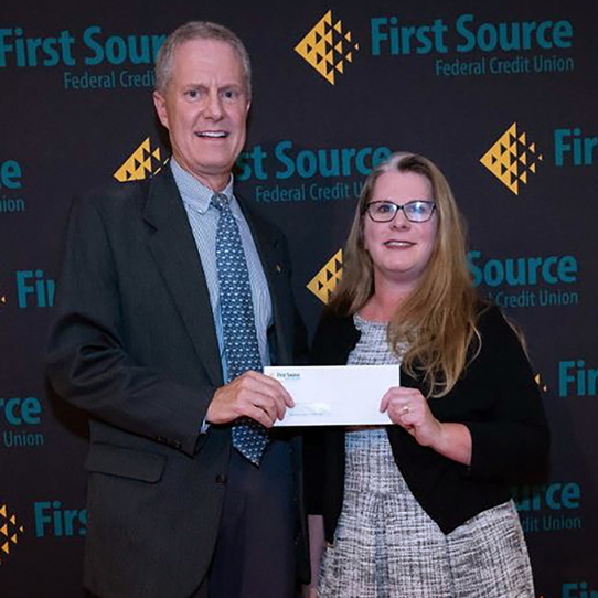 Caroline Lampert receiving a grant from a First Source representative