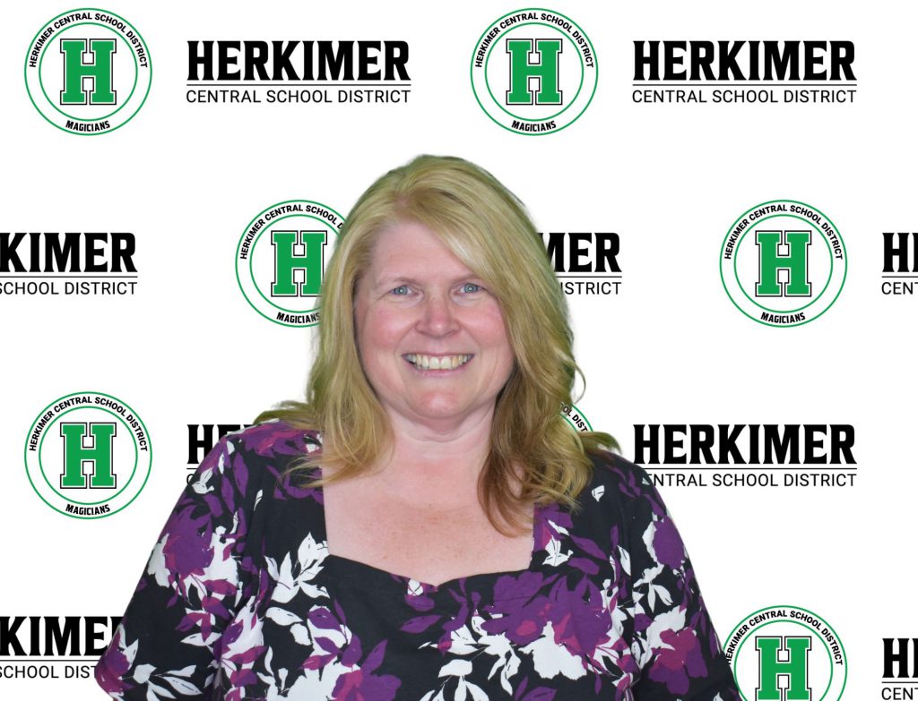 Herkimer District Treasurer Michele Gilbert in front of Herkimer logos background