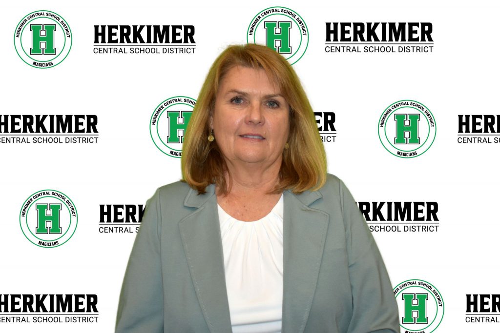 Board of Education member Diann Fischer in front of a Herkimer logos background