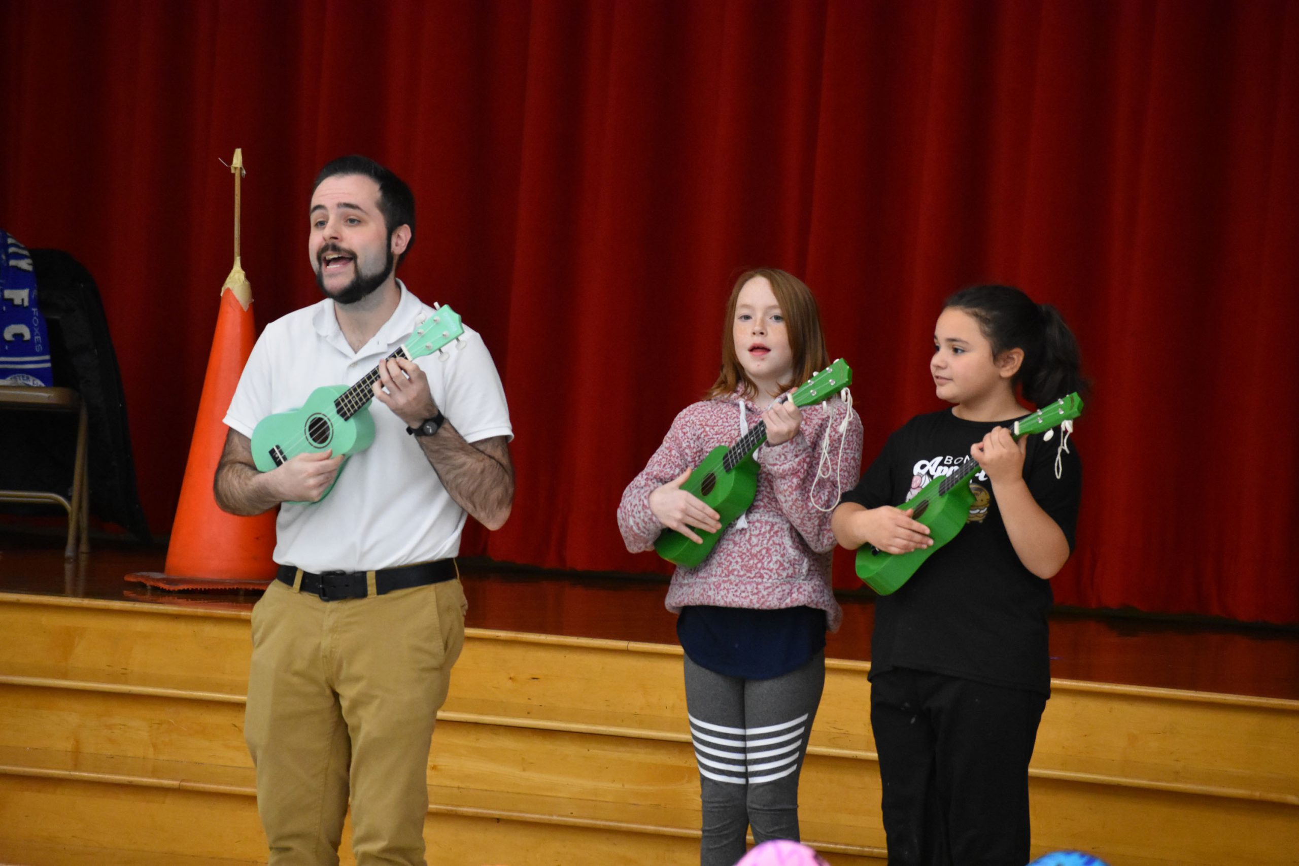 Teacher and students playing instruments in front of the stage