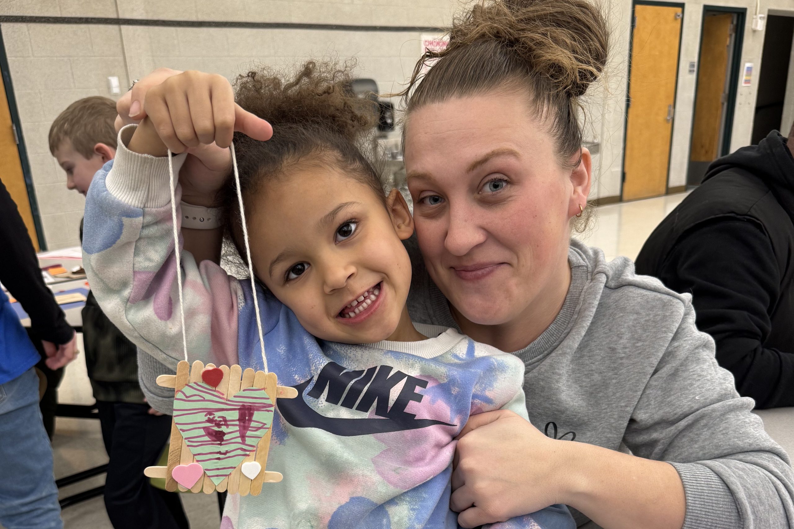 PreK student and adult holding up craft