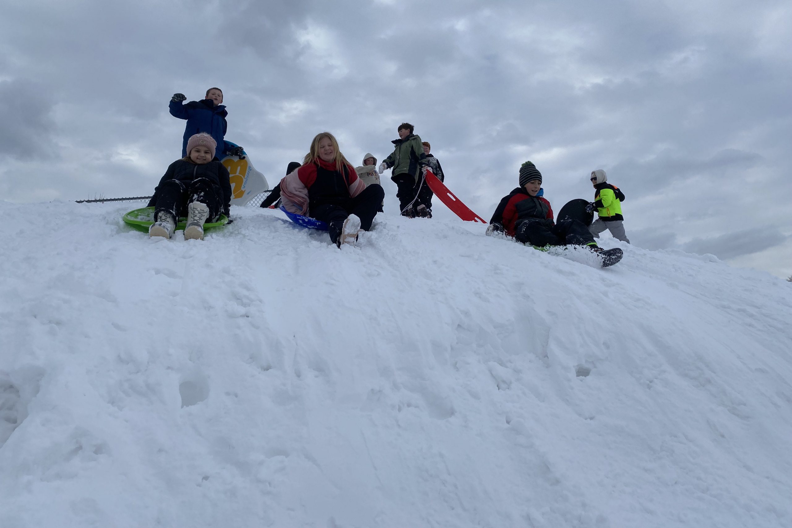 Elementary students playing in the snow on a hill of snow