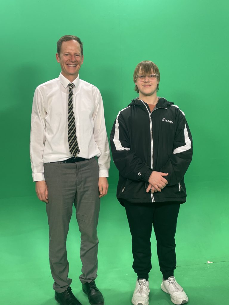 Herkimer junior Arthur Dadello and WKTV meteorologist Bill Kardas in front of a green screen