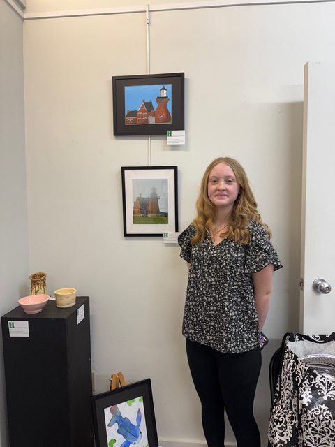 Student posing by artwork at exhibit