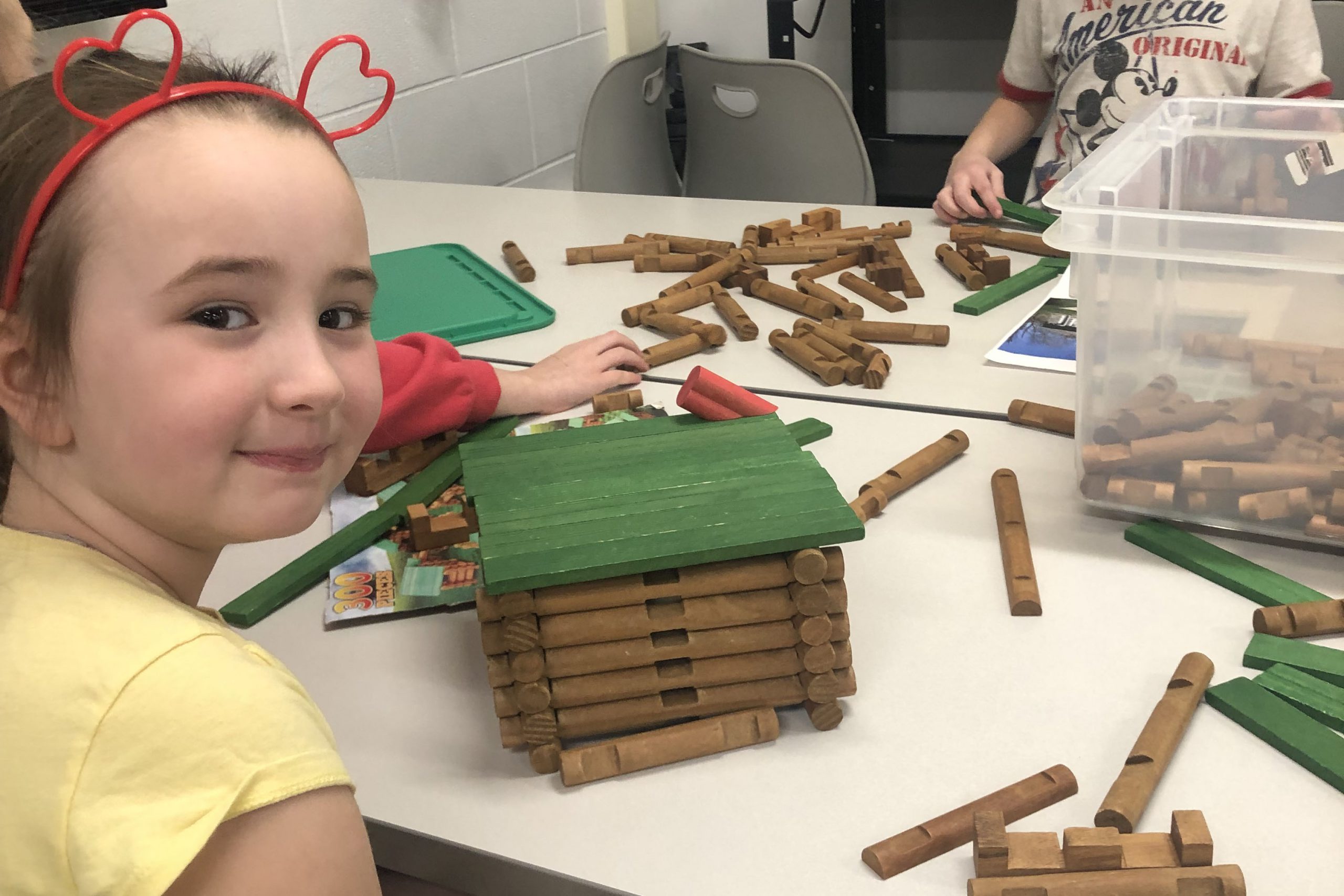 Student looking back at camera while building with Lincoln Logs