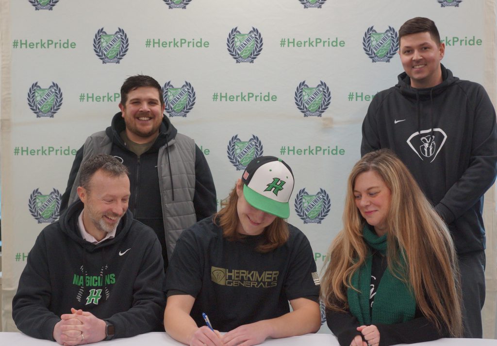 Logan Pullman signs commitment letter with family and coaches around him.