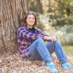 Student Logan Pullman sitting at the base of a tree