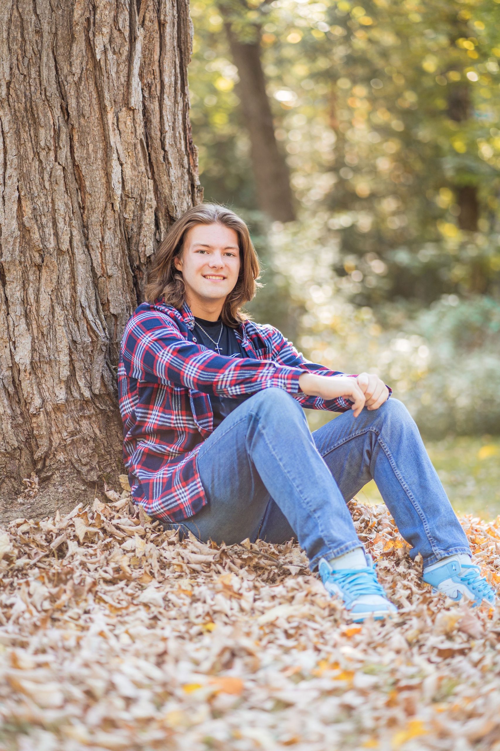 Student Logan Pullman sitting at the base of a tree